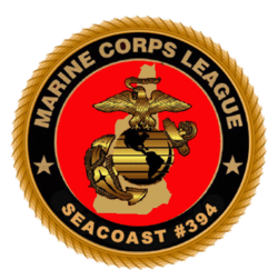 Officer of Marine Corps League with white button up shirt, black tie, and red hat with a holiday wreath behind him.