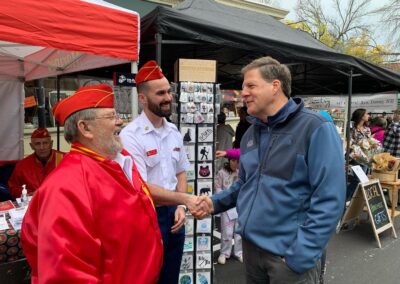 Gov Sununu shakes hands with Marine Corps League member hand in front of tent for MCL.