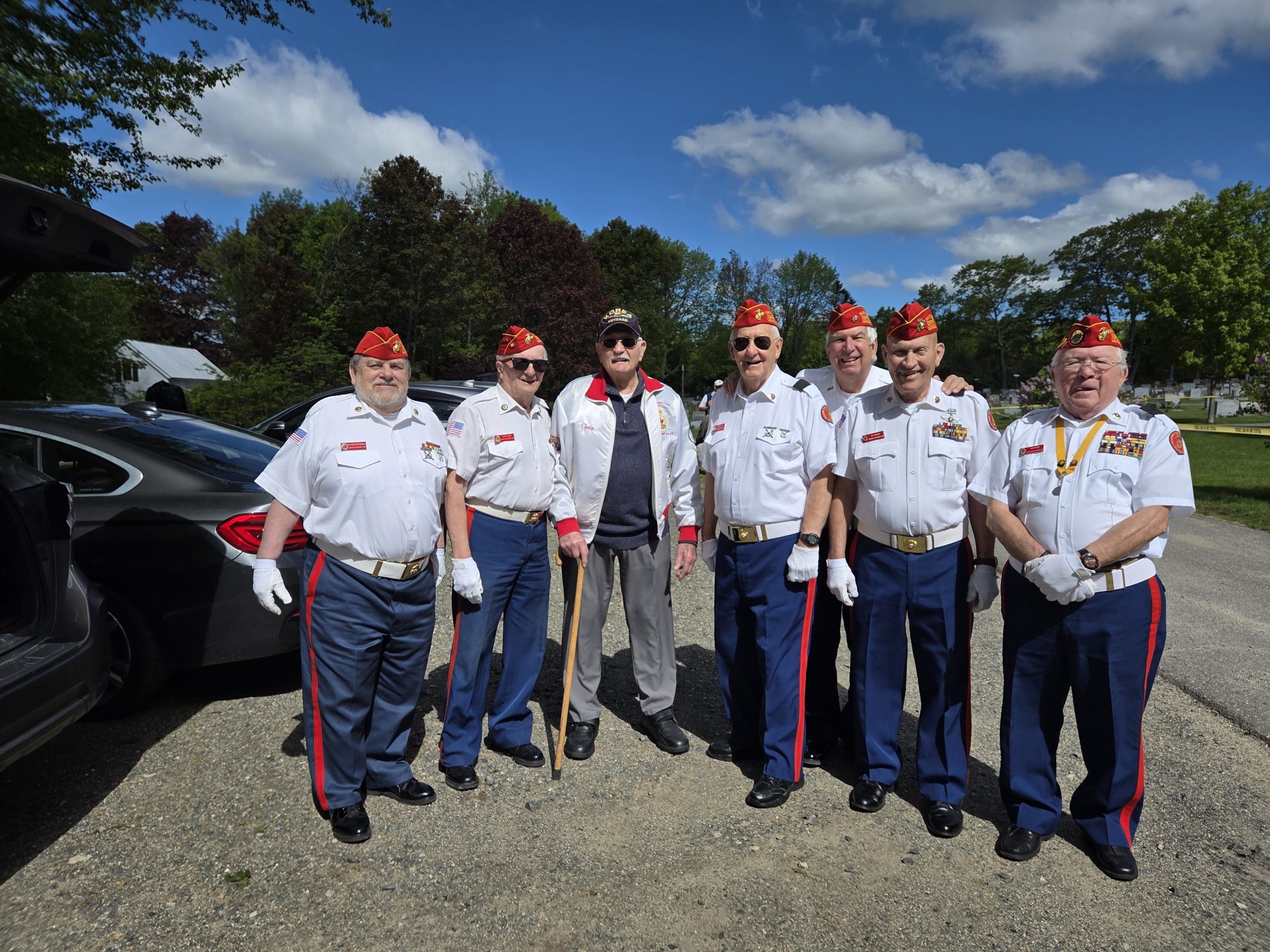 Marine Corps League members line up for a group picture in their official white shirt and blue pants and red cover uniform.