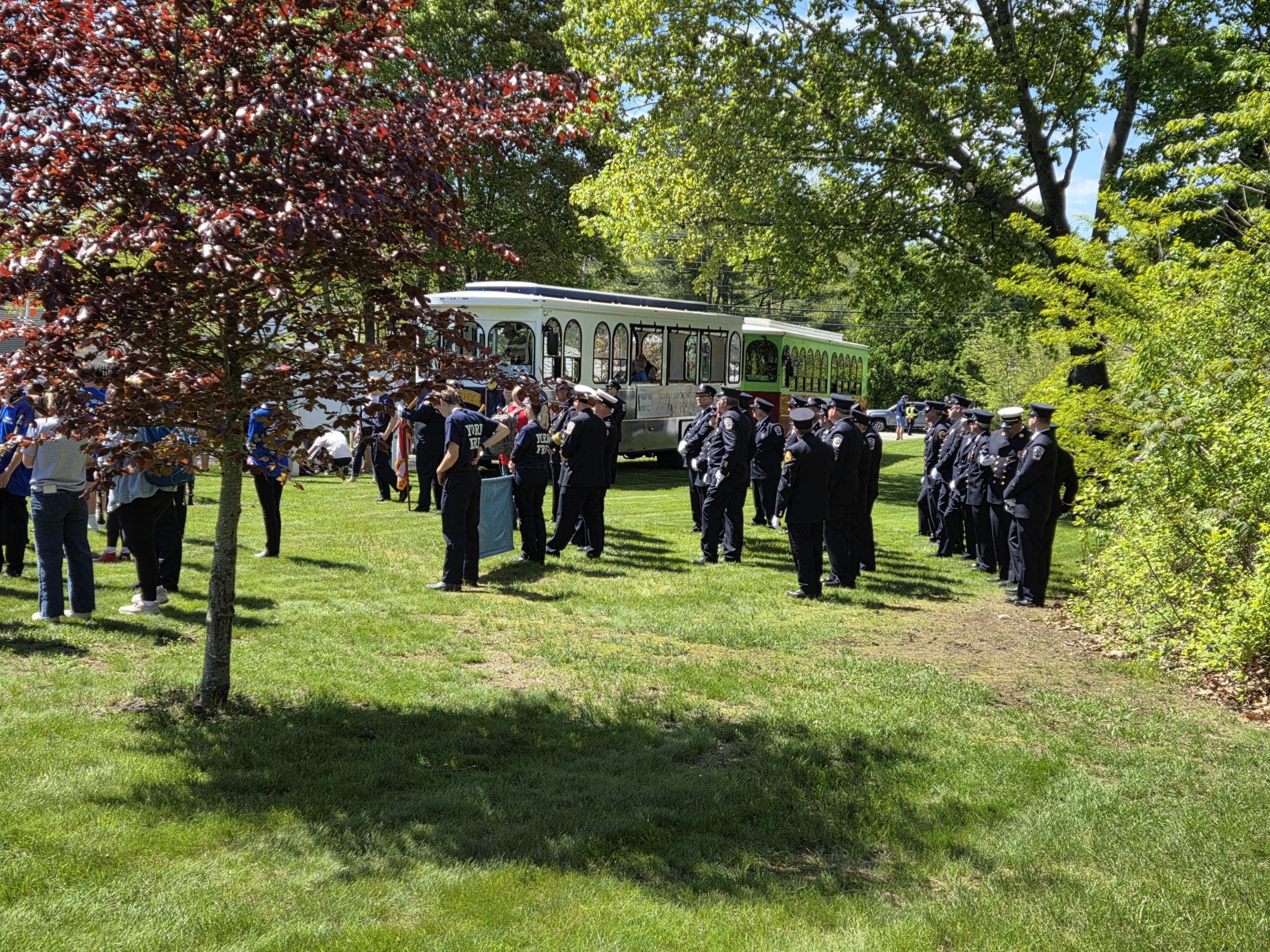 Men and women in dark blue uniforms line up to honor fallen at cemetery event.